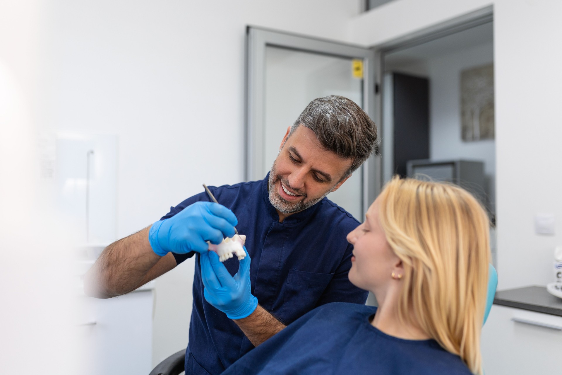 Dentist showing dental plaster mold to the patient. Dentist doctor showing jaw model at dental clinic, dental care concept. Dental care concept.
